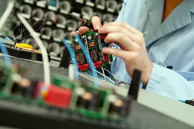 Technician handling a through-hole PCB assembly on a production line