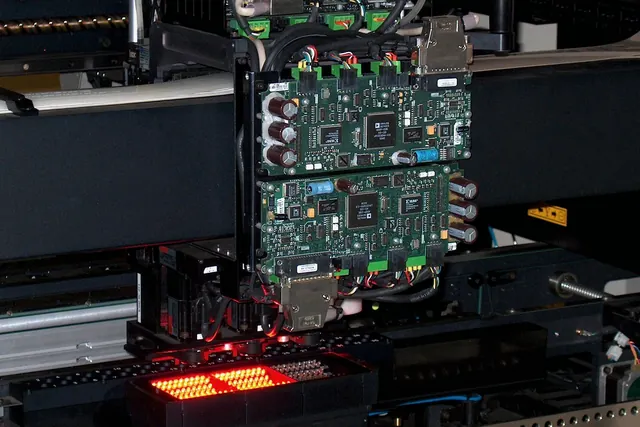 Representative SMT placement head positioning a populated PCB panel